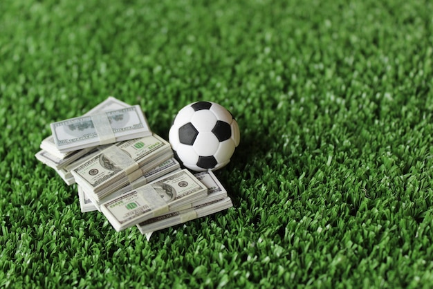 Selective focus image of soccer football and money on field Sport betting and bribery concept