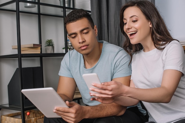 selective focus of interracial couple using gadgets in living room