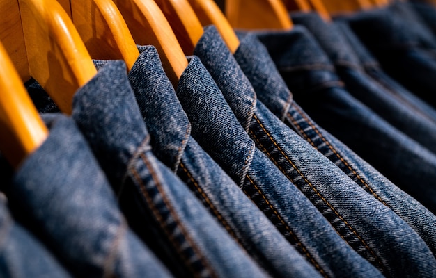 Selective focus on jacket jeans hanging on rack in clothes shop.