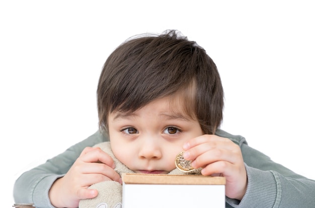 Selective focus kid boy putting pound coin on a money box