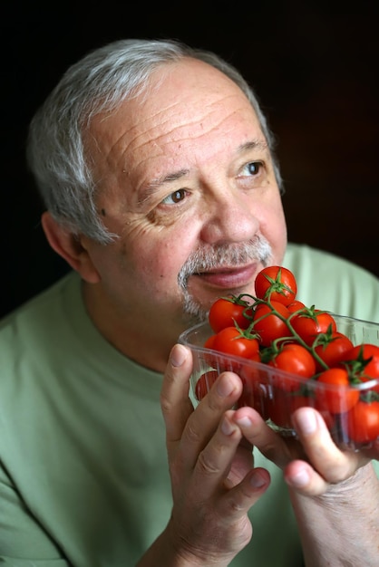 Selective focus Macro Cherry tomatoes in the hands of an elderly man The concept of healthy eating in older age