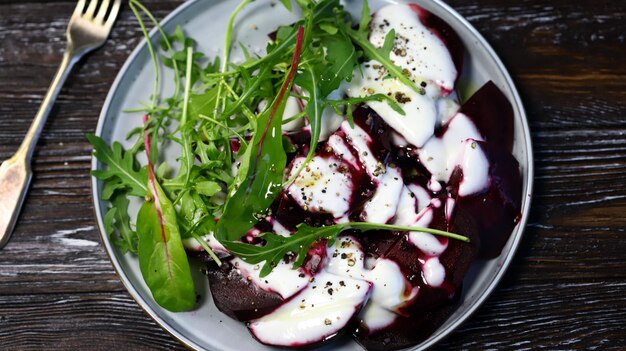 Selective focus. Macro. Vegan food. Beetroot arugula salad on a plate with yogurt sauce and olive oil. Healthy food. Diet salad.