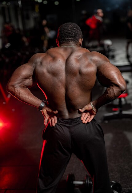 Selective focus on muscular back of a n athlete standing with back to the camera.