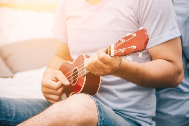 Foto il fuoco selettivo dell'uomo musicista sta suonando l'ukulele nel concetto di stile di vita del soggiorno