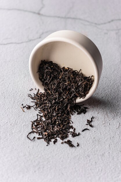 Селективный фокус заваривания натурального черного листового чая в макросе вертикального угла глиняной миски на светлом фоне ...