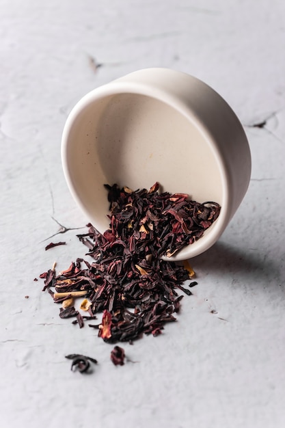 Selective focus natural black leaf tea brewing in a clay bowl vertical angle macro on a light backgr...