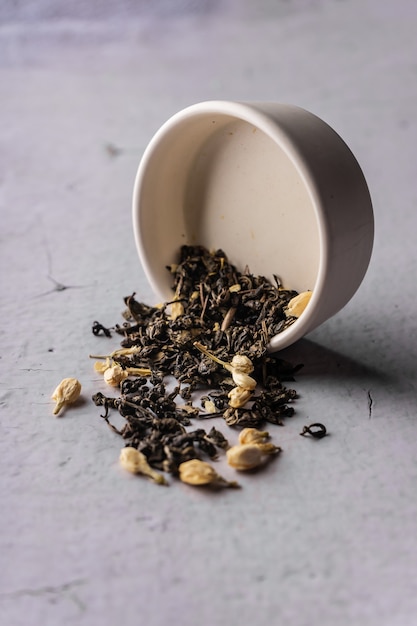 Selective focus natural black leaf tea with jasmine flowers
brewing in a clay bowl vertical angle ma...