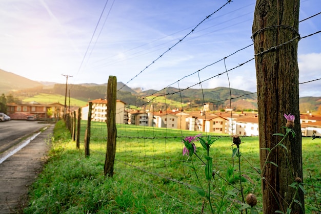 Selective focus on old wooden pole of wire fence on blur green grass field and city in valley Fence