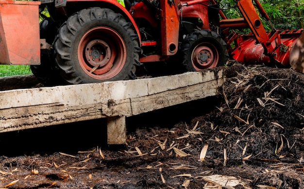 Focus selettivo sul trattore arancione che lavora al mucchio di compost in giardino biologico giardinaggio biologico