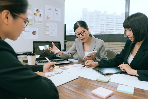 selective focus photo of company manager lady holding calculator reporting company planning during meeting with young business employee .