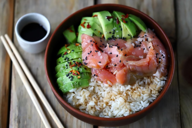 Selective focus. Poke bowl with salmon and avocado. Healthy food. Rice with avocado and fish. Sushi bowl.