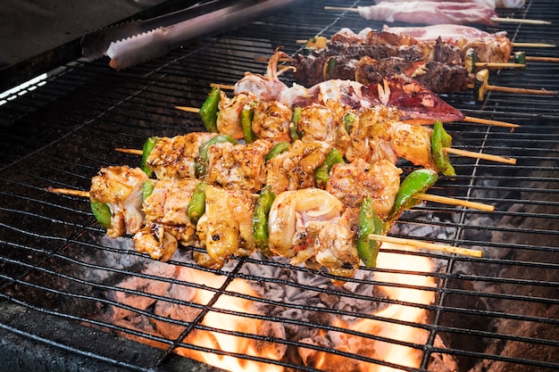 The selective focus pork Barbecue skewers on bamboo sticks . grilling food with vegetables on the stove for barbecue, Thailand Vietnamese or Chinese food. a barbecue in the open air.