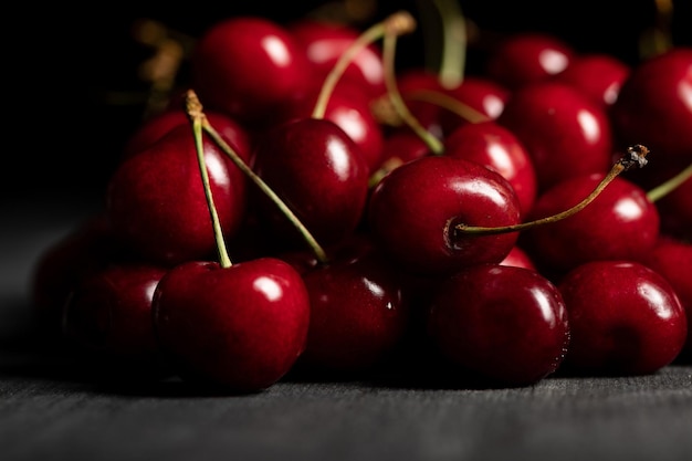 Selective focus of red delicious cherries scattered on wooden dark table