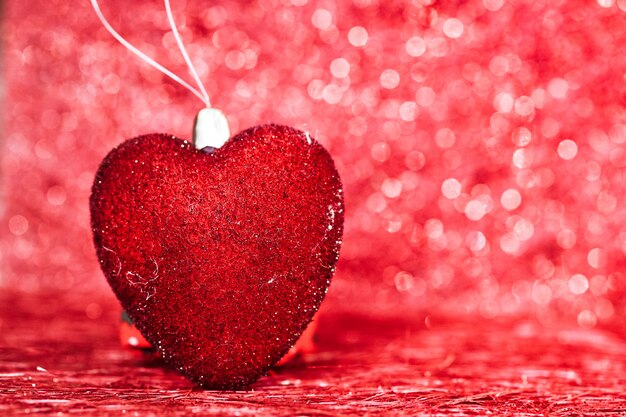 Selective focus on red heart shape on red blurred bokeh background with copy space 