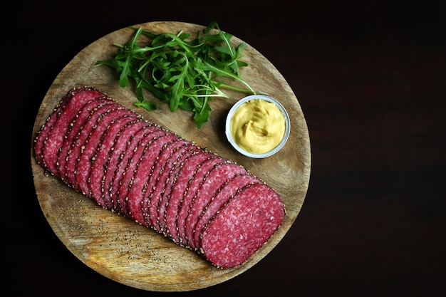 Selective focus Salami slices with black pepper on a wooden board