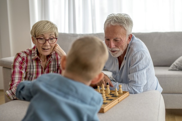 Selective focus shot of grandmother and grandfather  playing chess with grandson