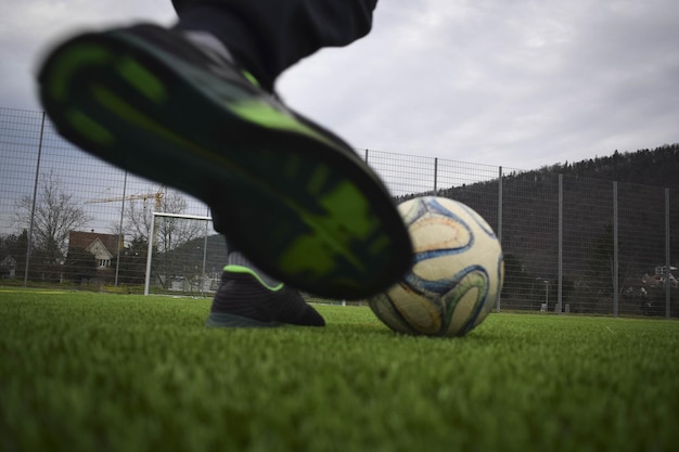 Selective focus shot of a male playing with the ball on a football stadium