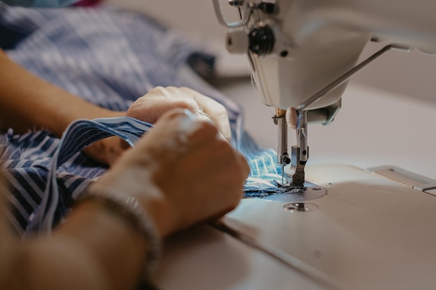 Selective focus shot of seamstress hands working on sewing machine