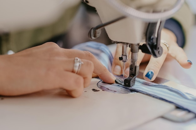 Selective focus shot of seamstress hands working on sewing machine