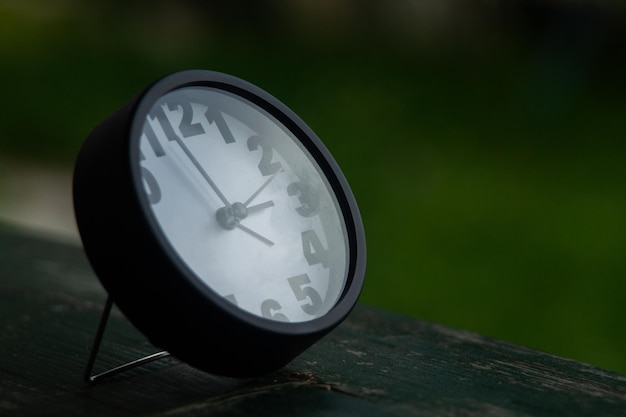 Selective focus shot of a small black alarm clock on a wooden surface