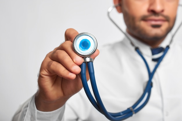 Selective focus on a stethoscope male doctor is holding out  copyspace medicine medical health healthcare professionalism trustworthy confident specialist skilled professional.