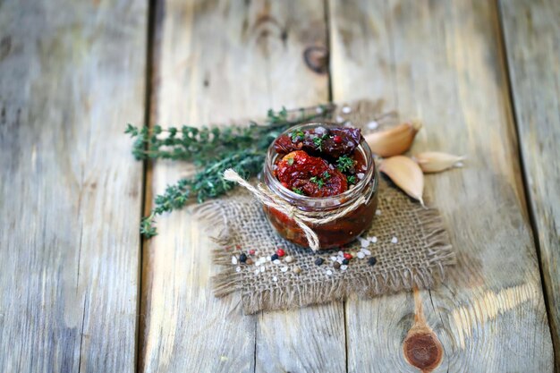 Selective focus. Sun-dried tomatoes in a jar with spices and garlic.