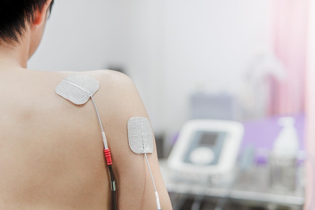 Selective focus on TENS Electrode Pads prepare for treatment on shoulder pain Electro stimulation machine in rehab room on the background in hospital health problem and medical concept