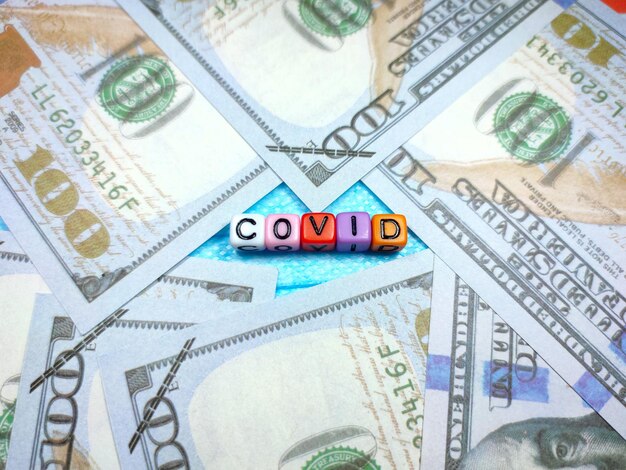 Selective focus of text Covid19 from colorful cube on face mask with banknote