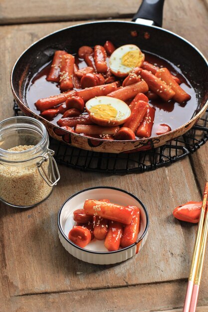 Selective Focus Topokki or Tteokbokki is Stir-fried Rice Cake with Vegetables and Fish Cake in Spicy Sauce Top with Sesame Seed, Famous and Popular Korean Street Food