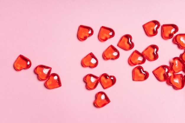 Selective focus. Valentine's day card. glass red hearts scattered on a pink background. the view from the top. copyspace