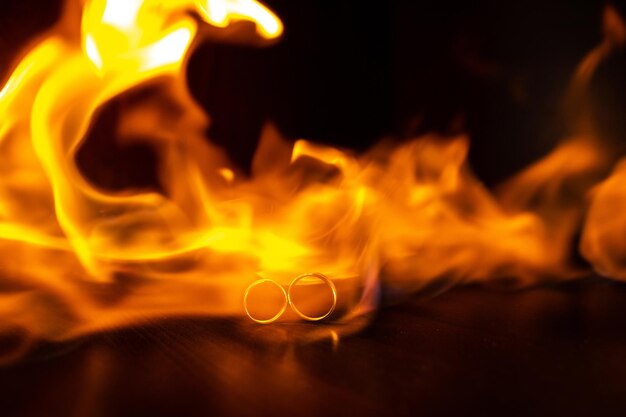 Selective focus Wedding rings on fire with reflection on black