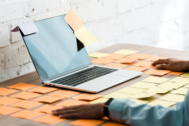 Photo selective focus of woman sitting near laptop with blank screen and sticky notes