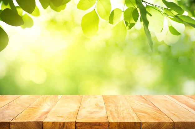 Selective focus of wood table top on blur green trees