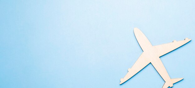 Selective focus of wooden airplane model emitting fresh green leaves on blue background.