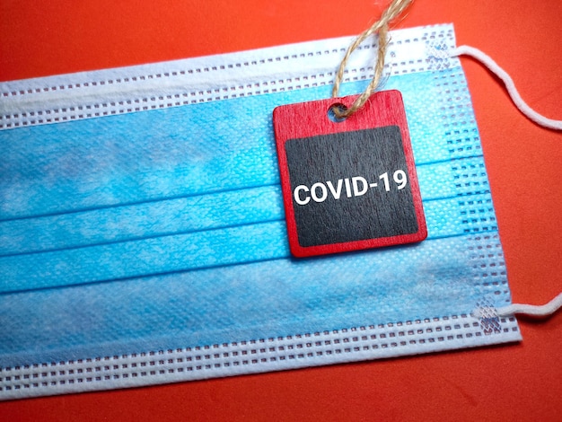 Selective focus of a wooden board and copy and face mask with red background