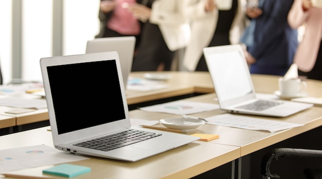 Selective focus on working desk, group of unrecognizable businesswomen standing together in office at breaking time. Female employee teamwork taking with relax in blur background.