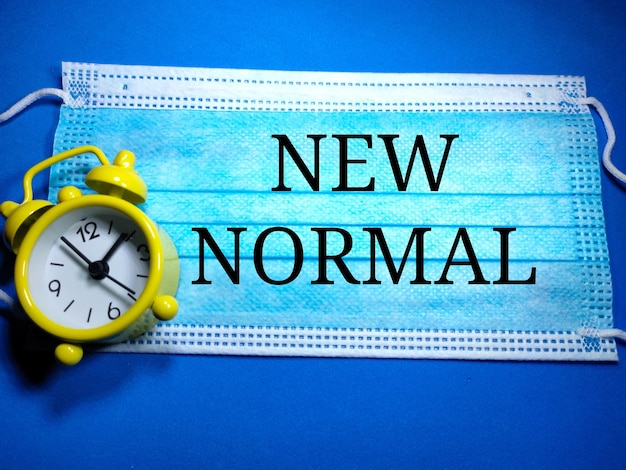 Photo selective focus of a yellow clock and copy and text space on a face mask with blue background