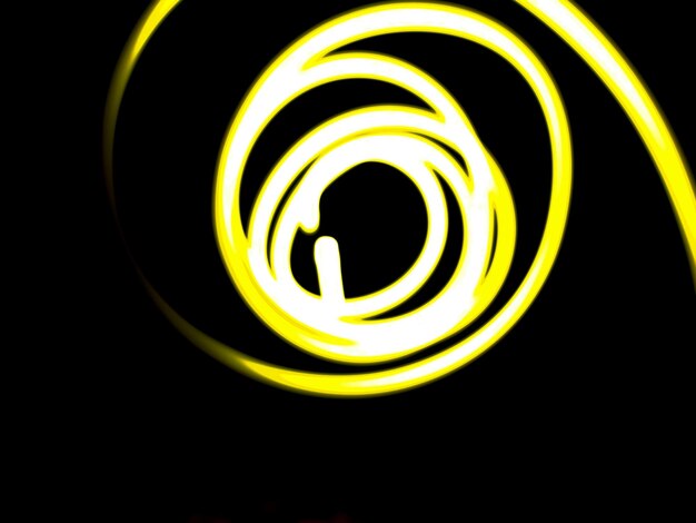 Selective focusA yellow light paintinglong exposure photography simple pattern against a black backgroundShot were noise and film grain