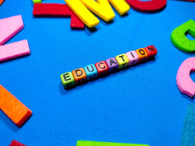 Selective focusColorful dice with word EDUCATION on blue backgroundShot were noise and film grain