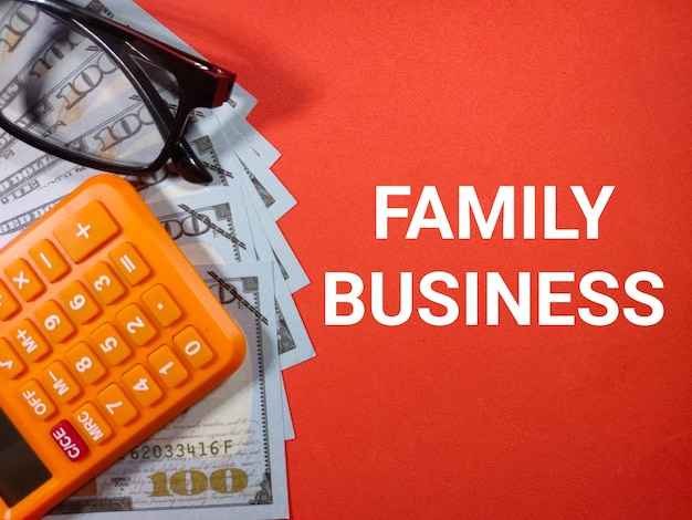 Selective focusWord FAMILY BUSINESS with calculatorglasses and dollar money on red backgroundBusiness concept