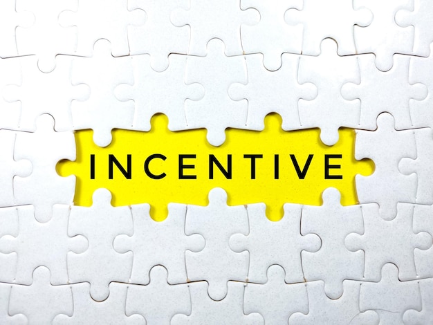 Selective focusWord INCENTIVE with jigsaw puzzle on yellow backgroundBusiness concept