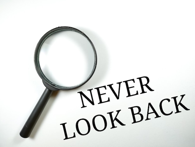 Selective focusWord NEVER LOOK BACK with magnifying glass on white backgroundBusiness concept