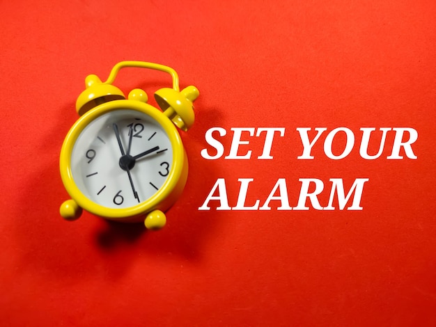 Foto messa a fuoco selettivaword imposta la tua sveglia con l'orologio su sfondo rossoconcetto di tempo