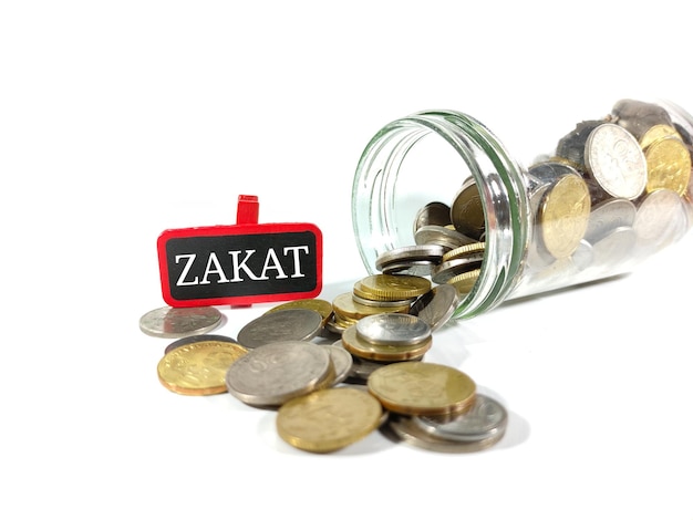 Selective focusWord ZAKAT on wooden board with coins and glass jar