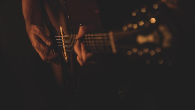 手が見える状態でアコースティック ギターを演奏するミュージシャンの選択的なショット