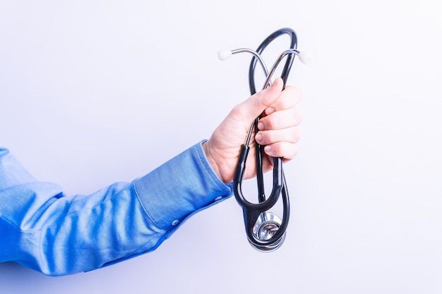 Selective view of woman's hand in blue shirt holding a medical stethoscope. medical tests concept. general medicine with copy space