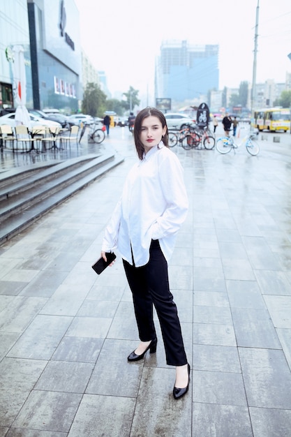 Self assured female director with red lips poses near office building