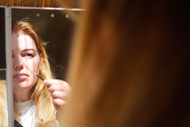 Photo self-care face of young beautiful healthy woman looking in the mirror beautiful woman ready