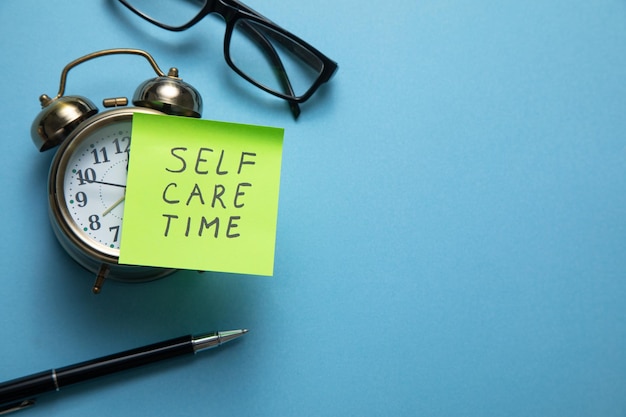 Photo self care time on sticky note with a clock and business objects