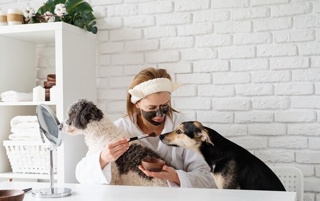 Photo self care young caucasian woman wearing bathrobes doing spa procedures with her dog